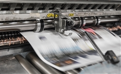 A newspaper mid-print in large industrial printer. Photo by Bank Phrom via Unsplash.